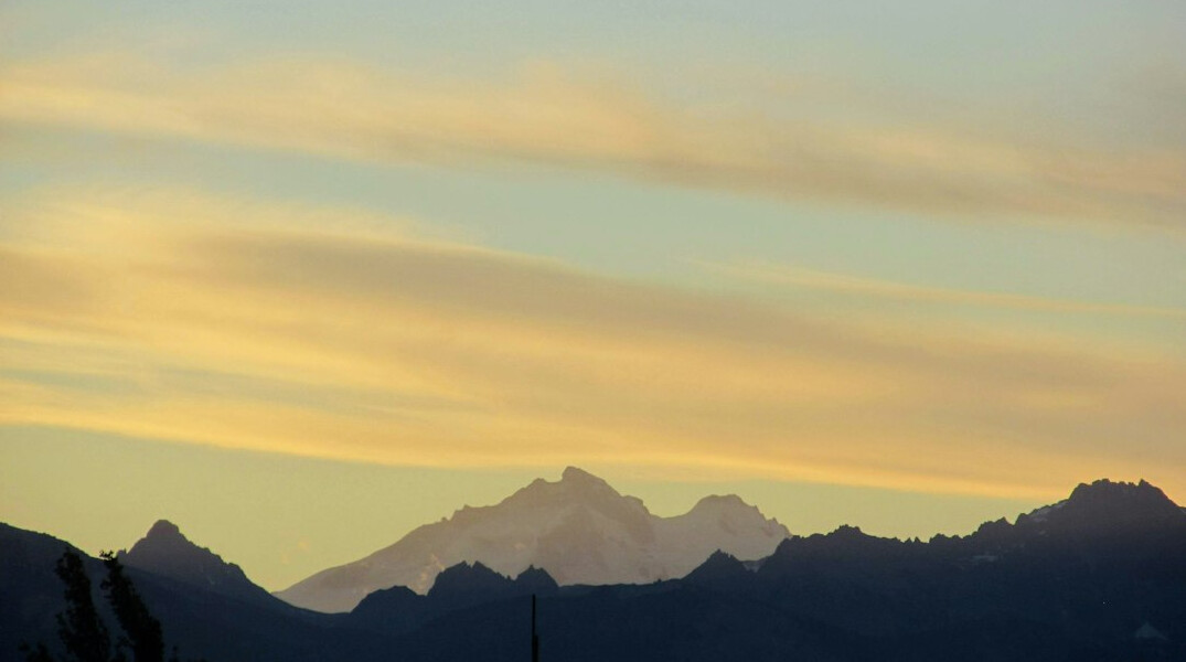 Silhouette of Andes mountains reflected in still water at dusk